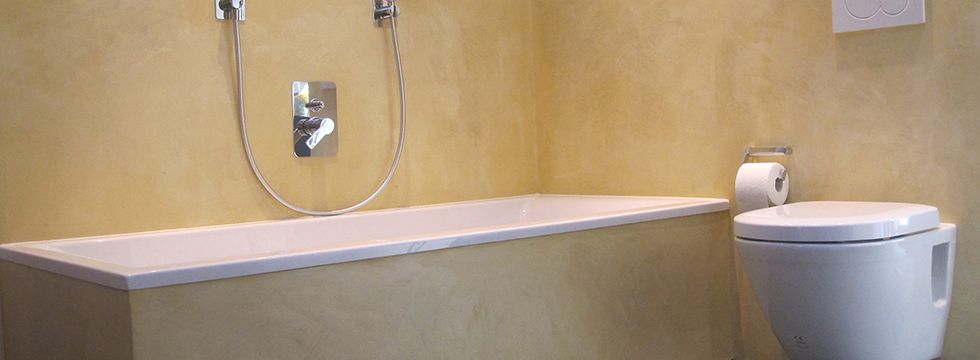 Badezimmer mit eingebauter Wanne, fugenlosem Wandbelag und Wand-WC